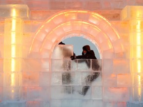 کارگران یک بلوک یخی را روی یک سازه یخی در محل جشنواره بین‌المللی یخ و برف هاربین قبل از افتتاح آن در هاربین، چین، ۱۶ دسامبر ۲۰۲۰ قرار می‌دهند.