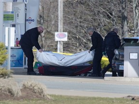 Workers with the medical examiner's office remove a body from a gas bar in Enfield, N.S. on Sunday, April 19, 2020.