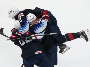 Arthur Kaliyev (No. 28), Drew Helleson (No. 2) and Jake Sanderson (No. 8) of the United States celebrate the game-winning goal against Finland during the 2021 IIHF World Junior Championship semifinals at Rogers Place on January 4, 2021.