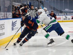 Connor McDavid of the Edmonton Oilers battles against Alexander Edler of the Vancouver Canucks at Rogers Place in Edmonton on on Jan. 13, 2021.