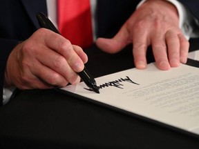 U.S. President Donald Trump signs executive orders extending coronavirus economic relief, during a news conference in Bedminster, N.J., Aug. 8, 2020.