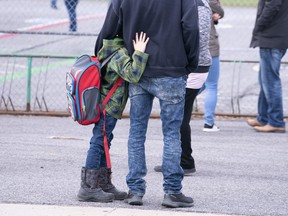 A boy hugs his father as he waits to be called to enter the schoolyard the Marie-Derome School in Saint-Jean-sur-Richelieu, Que. on Monday, May 11, 2020.