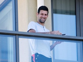 Novak Djokovic stands on his balcony at the accommodation where he is quarantining in advance of the Australian Open to be played in Melbourne, Australia, Tuesday, Jan. 19, 2021.