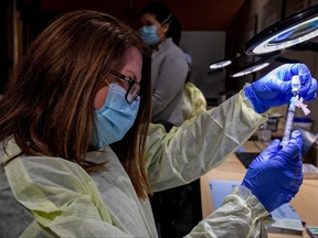 Pharmacy technician supervisor Tamara Booth Rumsey prepares a Pfizer-BioNTech COVID-19 vaccine at The Michener Institute, in Toronto, Jan. 4, 2021.