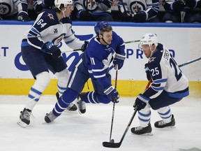 Winnipeg Jets defenceman Logan Stanley (left) checks Maple Leafs forward Zach Hyman during the first period in Toronto on Monday night. Stanley was making his NHL debut.