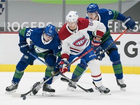 Canucks' Quinn Hughes (43) and Tyler Myers (57) check Canadiens' Corey Perry (94) in the third period at Rogers Arena in Vancouver on Saturday, Jan. 23, 2021.