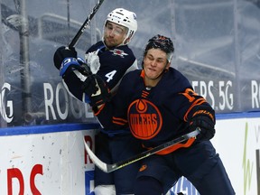 Edmonton Oilers forward Jesse Puljujarvi (13) battles Winnipeg Jets’ Neal Pionk (4) at Rogers Place in Edmonton on Monday, Feb. 15, 2021.