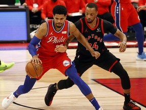 76ers' Tobias Harris (left) drives to the basket as Raptors' Norman Powell defends during the first half at Amalie Arena in Tampa, Fla., Tuesday, Feb. 23, 2021.
