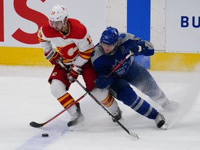 Calgary Flames' Johnny Gaudreau (left) and Maple Leafs' Zach Hyman battle for the puck during the second period at Scotiabank Arena on Wednesday, Feb. 25, 2021.