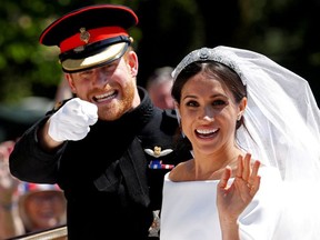 Britain's Prince Harry gestures next to his wife Meghan as they ride a horse-drawn carriage after their wedding ceremony at St George's Chapel in Windsor Castle in Windsor, Britain, May 19, 2018.