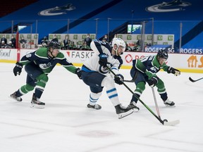 Vancouver Canucks forward Brock Boeser (6) and forward Elias Pettersson (40) check Winnipeg Jets forward Pierre-Luc Dubois (13) in the first period at Rogers Arena in Vancouver on Sunday, Feb. 21, 2021.