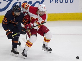 The Edmonton Oilers’ Darnell Nurse battles for the puck with the Calgary Flames’ Nikita Nesterov at Rogers Place in Edmonton on Saturday, Feb. 20, 2021.