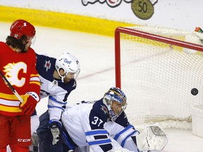 Calgary Flames defenceman Rasmus Andersson battles Winnipeg Jets goalie Connor Hellebuyck in first-period action at the Scotiabank Saddledome in Calgary on Tuesday, Feb. 9.