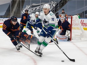 EDMONTON, AB - JANUARY 14: Slater Koekkoek #20 of the Edmonton Oilers defends against Tanner Pearson #70 of the Vancouver Canucks at Rogers Place on January 14, 2021 in Edmonton, Canada.