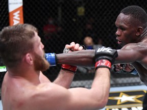 LAS VEGAS, NEVADA - MARCH 06: In this handout image provided by UFC, (R-L) Israel Adesanya of Nigeria punches Jan Blachowicz of Poland in their UFC light heavyweight championship fight during the UFC 259 event at UFC APEX on March 06, 2021 in Las Vegas, Nevada.