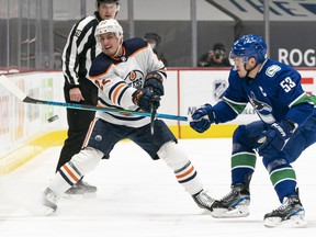 Bo Horvat (53) of the Vancouver Canucks competes for the puck against Tyson Barrie (22) of the Edmonton Oilers at Rogers Arena on March 13, 2021, in Vancouver.