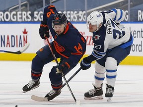 Winnipeg Jets forward Nikolaj Ehlers, right, and Edmonton Oilers forward Devin Shore chase a loose puck during the third period at Rogers Place in Edmonton, March 20, 2021.