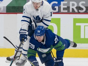 Canucks forward Antoine Roussel (26) checks Toronto Maple Leafs forward Zach Hyman (11) in the first period at Rogers Arena on Saturday night.