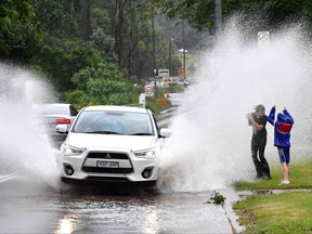 Children react as they are sprayed with floodwaters while motorists commute on a road near Warragamba Dam in Sydney on March 21, 2021, as Sydney braced for its worst flooding in decades after record rainfall caused its largest dam to overflow and as deluges prompted mandatory mass evacuation orders along Australia's east coast.