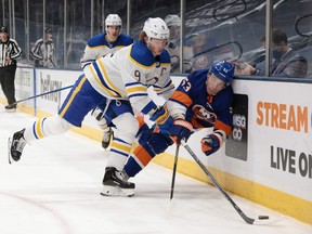 Jack Eichel of the Buffalo Sabres checks Casey Cizikas of the New York Islanders into the boards during the second period at the Nassau Coliseum on March 7, 2021 in Uniondale, N.Y.