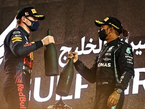 Red Bull's Dutch driver Max Verstappen, left, greets Mercedes' British driver Lewis Hamilton on the podium after the Bahrain Formula One Grand Prix at the Bahrain International Circuit in the city of Sakhir on March 28, 2021.