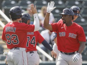 Josh Ockimey, right, of the Red Sox celebrates with teammates after hitting a three-run home run against the Twins during the eighth inning of a Grapefruit League game at Hammond Stadium in Fort Myers, Fla., Sunday, March 14, 2021.