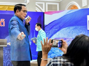 This handout from the Royal Thai Government taken and released on March 9, 2021 shows Thailand's Prime Minister Prayut Chan-O-Cha spraying hand sanitiser at journalists in an attempt to avoid questions about the cabinet reshuffle during a press conference in Bangkok.