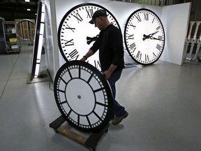 Dan LaMoore wheels a clock away at the Electric Time Company in Medfield, Mass. ahead of a change to Daylight Time.