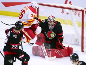 Ottawa Senators' Filip Gustavsson makes a save as Calgary Flames' Zac Rinaldo jumps out of the way of the shot during second period of NHL hockey action in Ottawa on Monday.