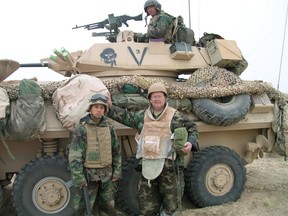 Columnist Matthew Fisher (right, on the ground) is pictured dressed in chemical weapon protection gear while south of Baghdad, Iraq, on March 22, 2003. The photo was taken during an early pause in the race for Baghdad during the 2003 Iraq invasion to oust Saddam Hussein from power.