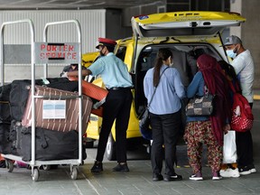 A porter loads luggage of recently arrived air travellers from New Delhi, after Canada temporarily barred passenger flights from India and Pakistan for 30 days, at Vancouver International Airport in Richmond, B.C., April 23, 2021.