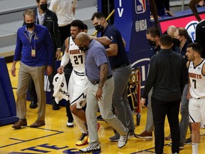 Nuggets guard Jamal Murray (27) is helped off the court after a knee injury in their game against the Warriors at Chase Center in San Francisco, Sunday, April 12, 2021.