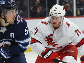 Winnipeg Jets centre Mark Scheifele (left) surveys his passing options with Carolina Hurricanes centre Lucas Wallmark defending in Winnipeg on Tues., Dec. 17, 2019.