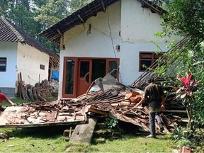 This handout picture taken and released on April 10, 2021 by Indonesian National Board for Disaster Management (BNPB) shows villagers beside a collapsed house at Tegalrejo village, in Blitar, East Java, after a 6.0 magnitude earthquake struck off the coast of Indonesia's Java island.