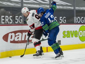 Senators centre Josh Norris (9) protects the puck during a battle along the boards with Canucks defenceman Quinn Hughes in the second period of Thursday's game at Rogers Arena in Vancouver.