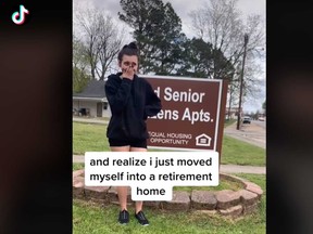 Madison Kohout, 19, poses in front of the "Senior Citizens Apartments" sign outside her home in a TikTok video.