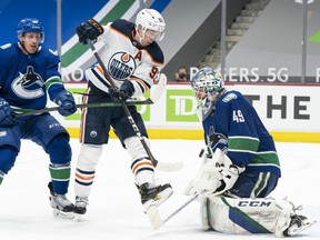 Goalie Braden Holtby #49 of the Vancouver Canucks stops Ryan Nugent-Hopkins #93 of the Edmonton Oilers in close during the third period of NHL action at Rogers Arena on April 16, 2021 in Vancouver, Canada. Nate Schmidt #88 of the Vancouver Canucks tries to help defend on the play.
