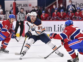 Connor McDavid (97) of the Edmonton Oilers skates the puck past Jake Evans (71) and Alexander Romanov (27) of the Montreal Canadiens during the first period at the Bell Centre on May 12, 2021 in Montreal.