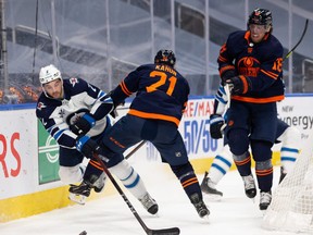 The Edmonton Oilers’ Dominik Kahun (21) hits the Winnipeg Jets’ Dylan DeMelo (2) next to Oilers teammate James Neal (18) during Game 2 of their NHL North Division playoff series at Rogers Place in Edmonton on Friday, May 21, 2021.