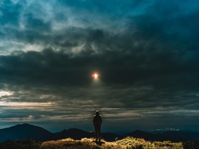 The UFO shines on a male standing on the mountain