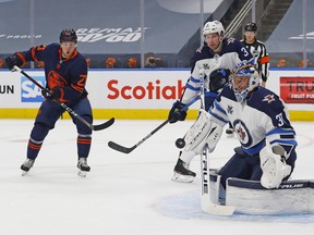 Oilers forward Dominik Kahun looks for a rebound in front of Jets goalie Connor Hellebuyck during the first period of Game 1 of their opening-round series in Edmonton last night. It was Hellebuyck’s 28th birthday yesterday.