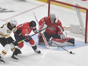 Washington Capitals right wing T.J. Oshie (77) clears the puck from Boston Bruins center Sean Kuraly (52) as goaltender Craig Anderson (31) looks on during the first period in game two of the first round of the 2021 Stanley Cup Playoffs at Capital One Arena.