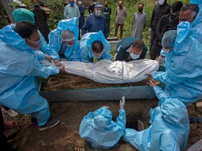 Relatives wearing protective gear prepare for the burial of a victim who died of COVID-19 during the funeral at a graveyard in Srinagar on May 7, 2021.