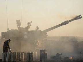 An Israeli soldier operates an artillery unit as it fires near the border between Israel and the Gaza Strip in Sderot, Israel, on Tuesday, May 18, 2021.