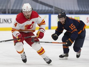 Edmonton Oilers Josh Archibald (15) and Calgary Flames Rasmus Andersson (4) skate for the puck during second period NHL action on Saturday, May 1, 2021 in Edmonton.