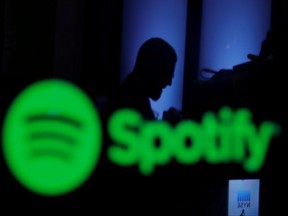 A trader is reflected in a computer screen displaying the Spotify brand before the company begins selling as a direct listing on the floor of the New York Stock Exchange in New York, April 3, 2018.
