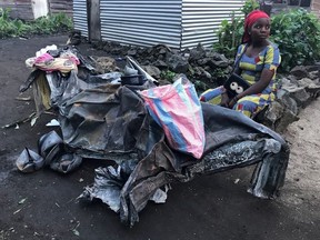Masika Joelle, 22, a local resident, sits next to a burnt iron sheet and utensils that she salvaged from the smouldering lava after the eruption of Mount Nyiragongo volcano, near Goma, in the Democratic Republic of Congo May 24, 2021.