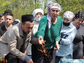 A mourner throws soil into the grave of Elvira Ignatieva, an English language teacher killed in the massacre at School Number 175, during a funeral at a cemetery in Kazan, Russia May 12, 2021.