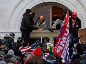 A mob of supporters of then-U.S. President Donald Trump climb through a window they broke as they storm the U.S. Capitol Building in Washington, U.S., January 6, 2021.