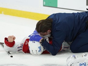 Jake Evans is tended to on the ice by Graham Rynbend, the Canadiens’ head athletic therapist, after suffering a concussion as a result of a violent check from the Jets’ Mark Scheifele during Game 1 of their North Division final playoff series Wednesday night in Winnipeg.